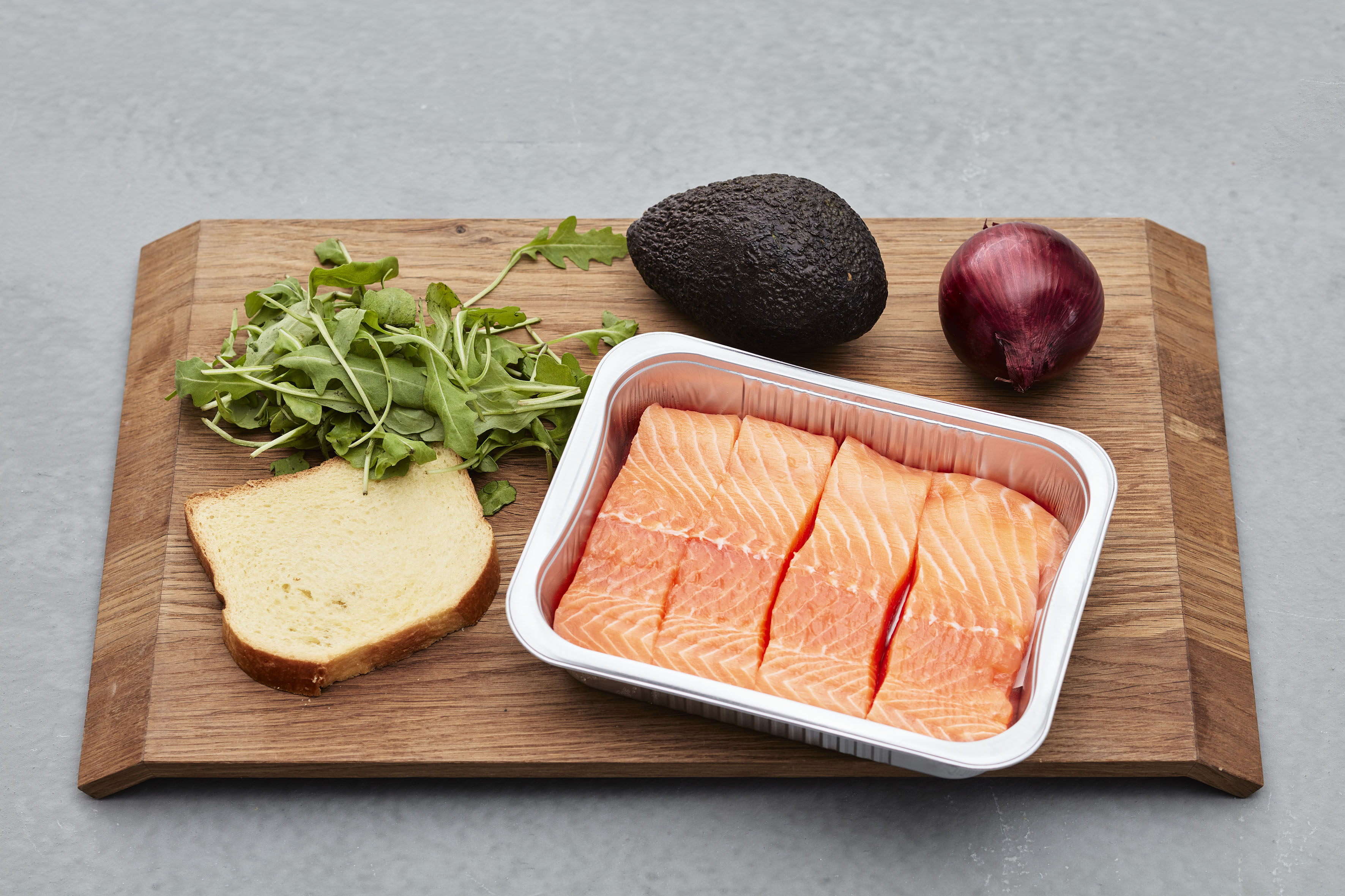 Lakseporsjoner og grønnsaker på skjærebrett